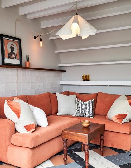 An orange sofa in a corner at The Lost Poet, a boutique hotel in Notting HIll